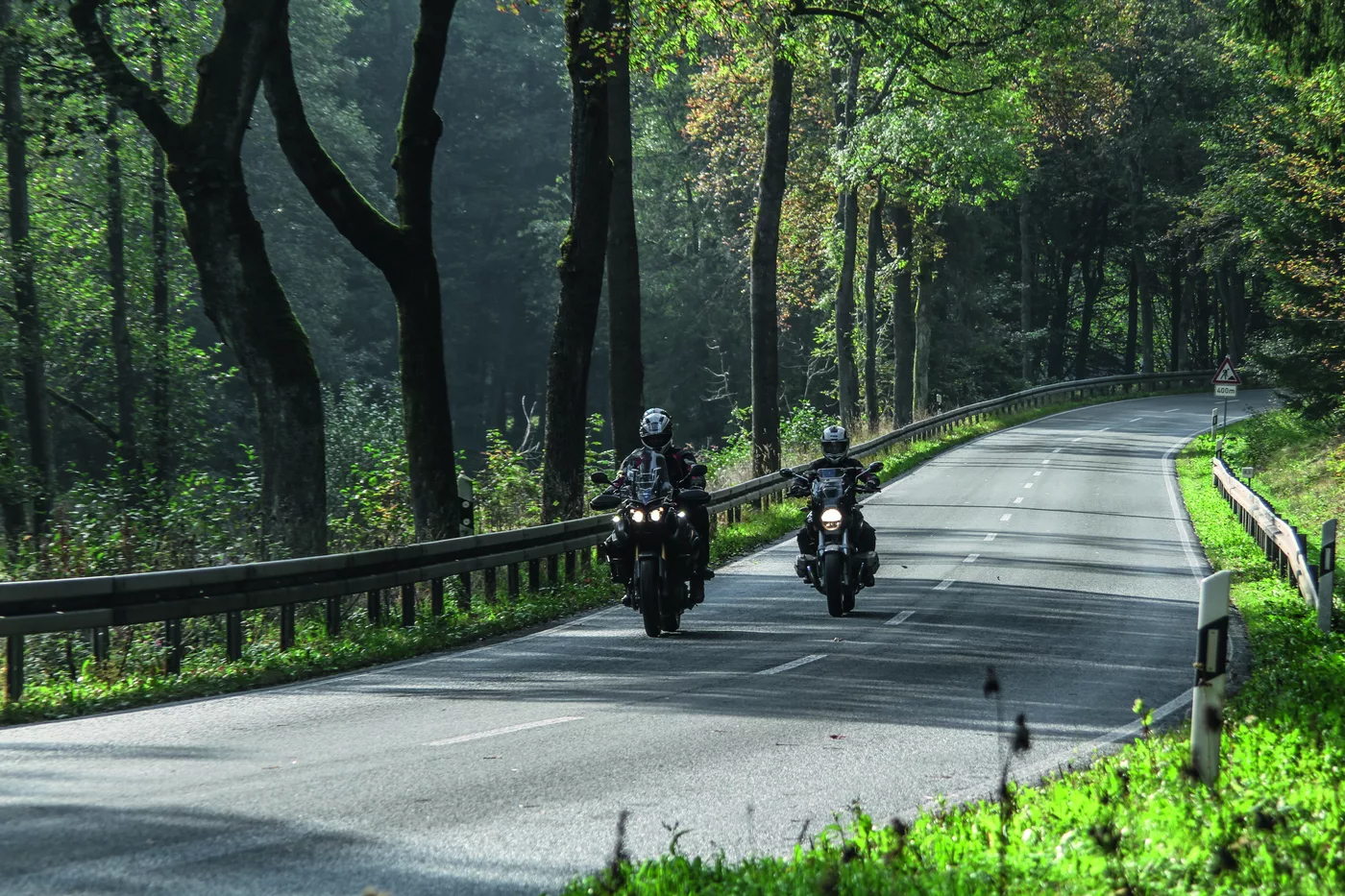 Zwei Motorräder auf einer von Bäumen gesäumten Straße am Morgen